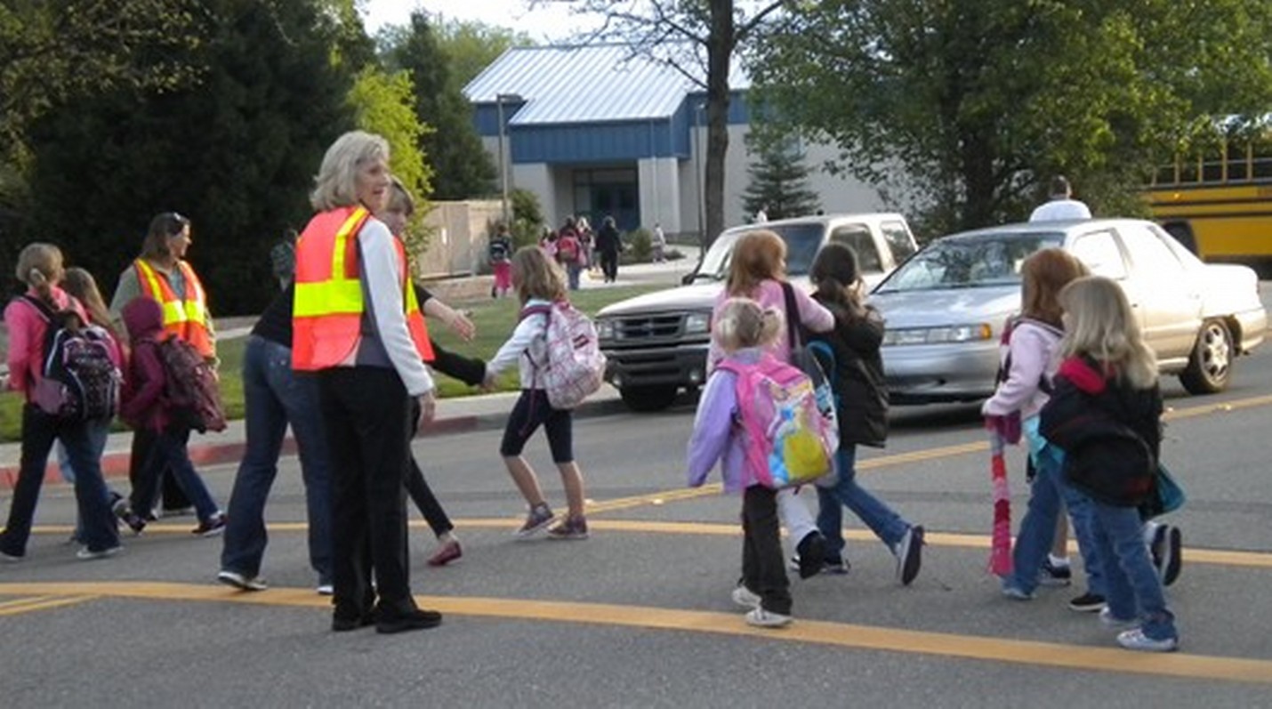 School children crossing the street safely with the help of crossing guards.